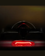 Rear close-up of an OPlace bike tail light glowing red at night