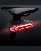 Close-up of red OPlace tail light mounted beneath a white bike saddle