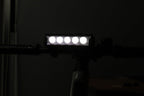 Multi-LED bike front light shining white from a handlebar-mounted position