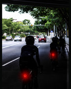 Cyclists riding on a city road with red rear lights visible in the distance