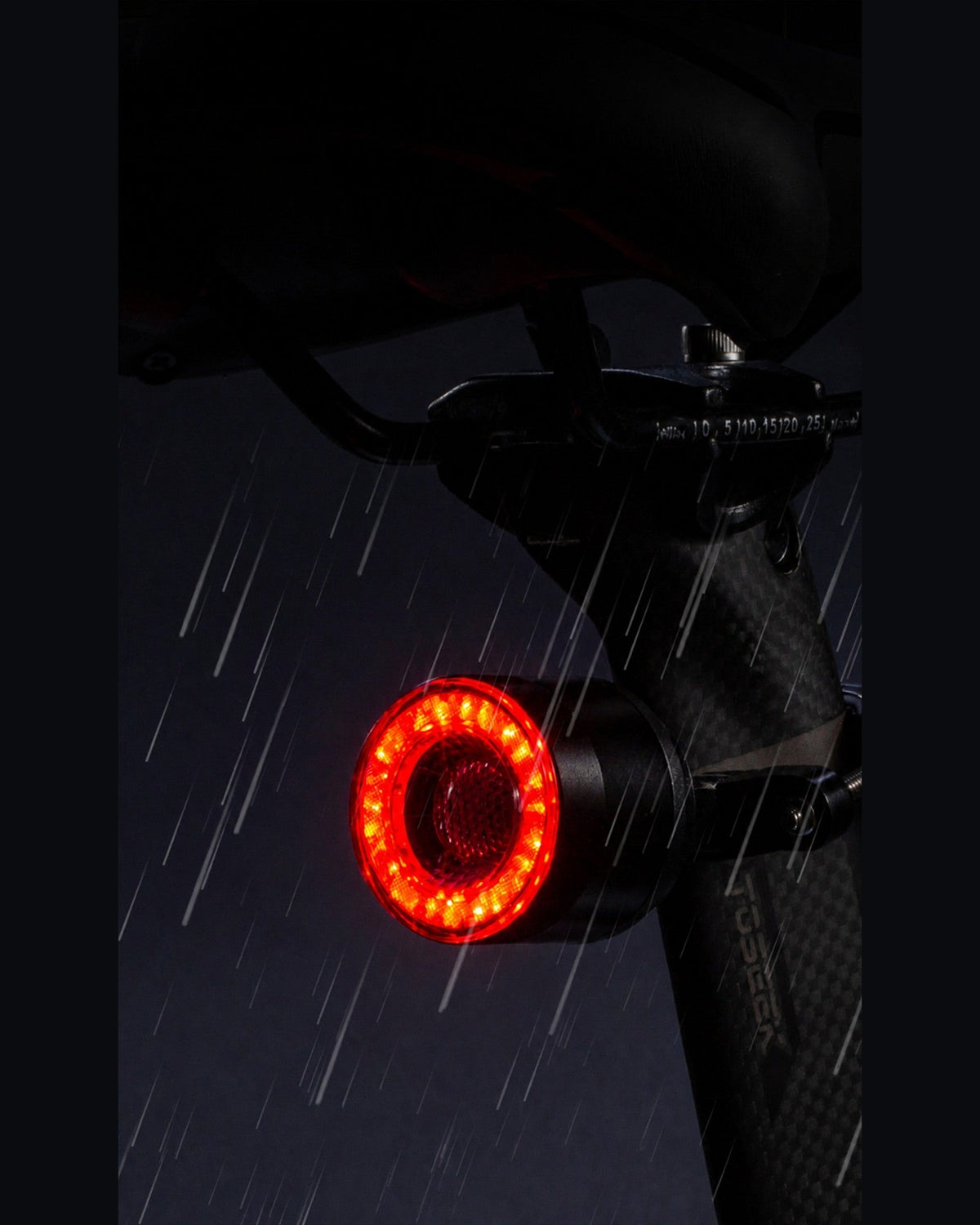 Round RGB halo bike light glowing red beneath a bicycle saddle in the rain