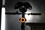 Rear bicycle view with an amber halo light glowing beneath the saddle