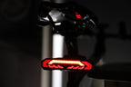 Red OPlace bike tail light mounted under a saddle indoors